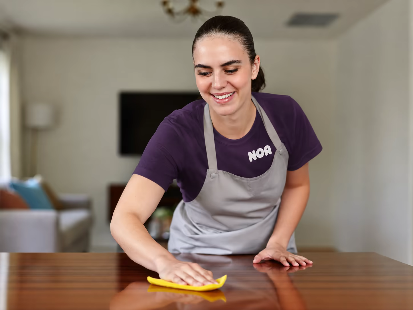 A cleaner wiping a wooden dining table in a bright living room